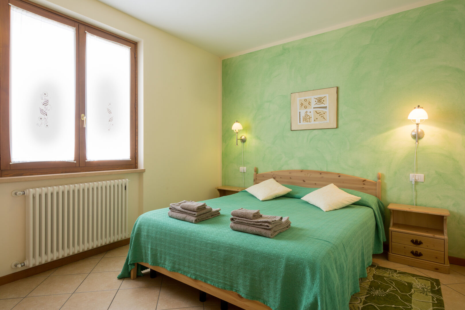 Appartamento Gli olivi: seconda camera con letto in legno chiaro e copriletto verde