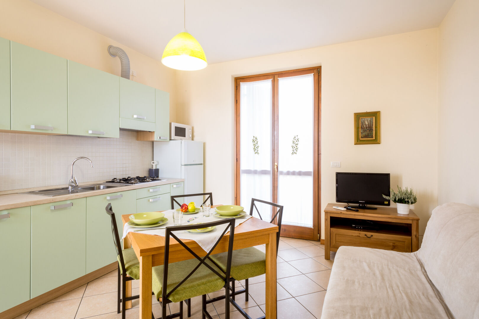 Appartamento con cucina verde menta, tavolo da pranzo e divano