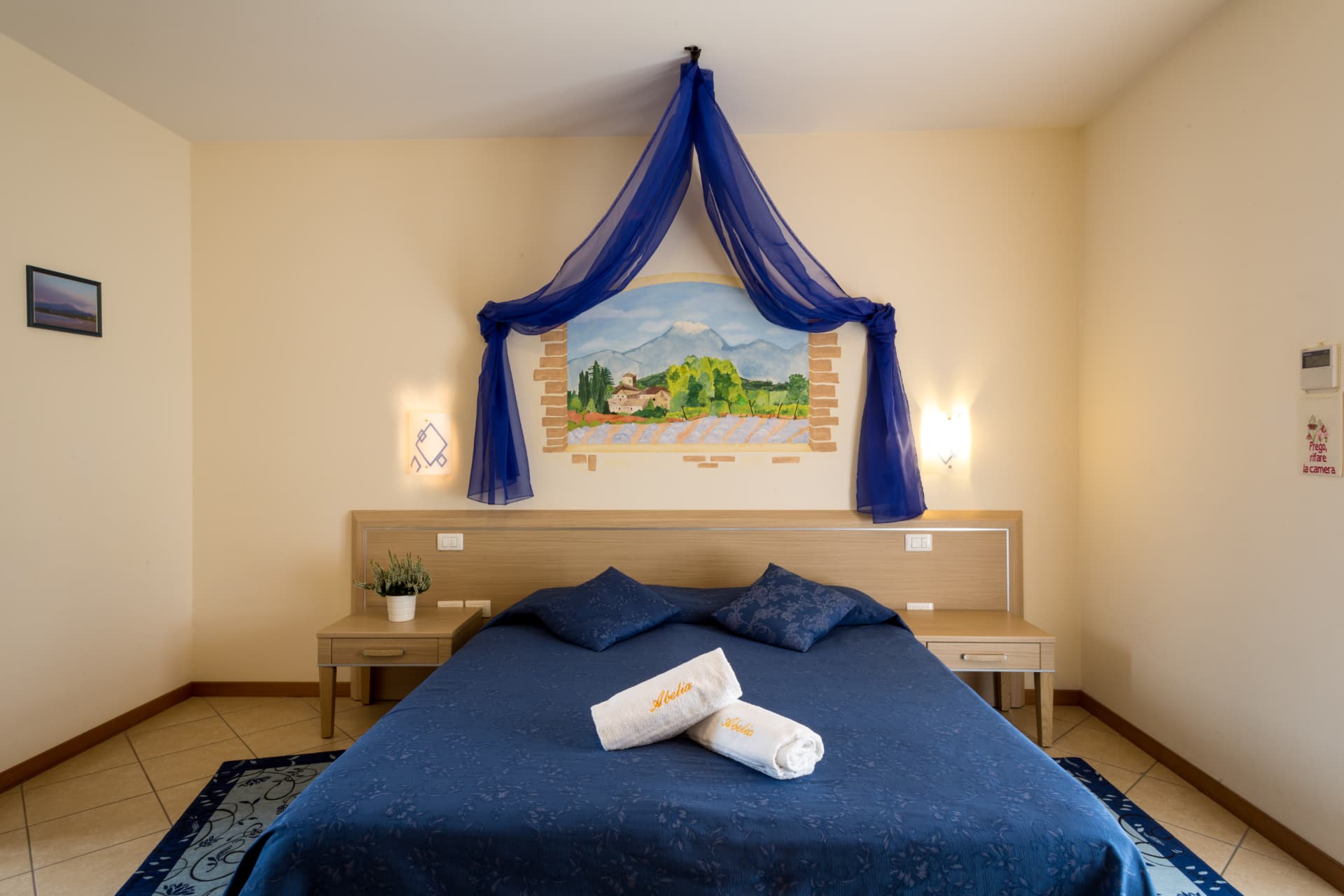 Camera degli anemoni: letto blu con baldacchino e affresco di paesaggio